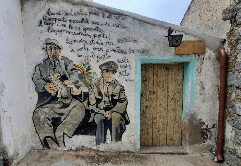 Fresque murale d’Orgosolo représentant deux hommes assis, peinte sur la façade d’une maison du village.